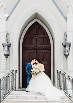 Wedding groom wearing Mystic Blue Tux with Bride in front of church doors.