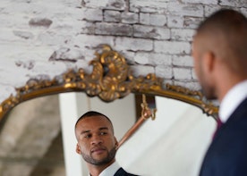 Groom trying on blue suit in front of a mirror