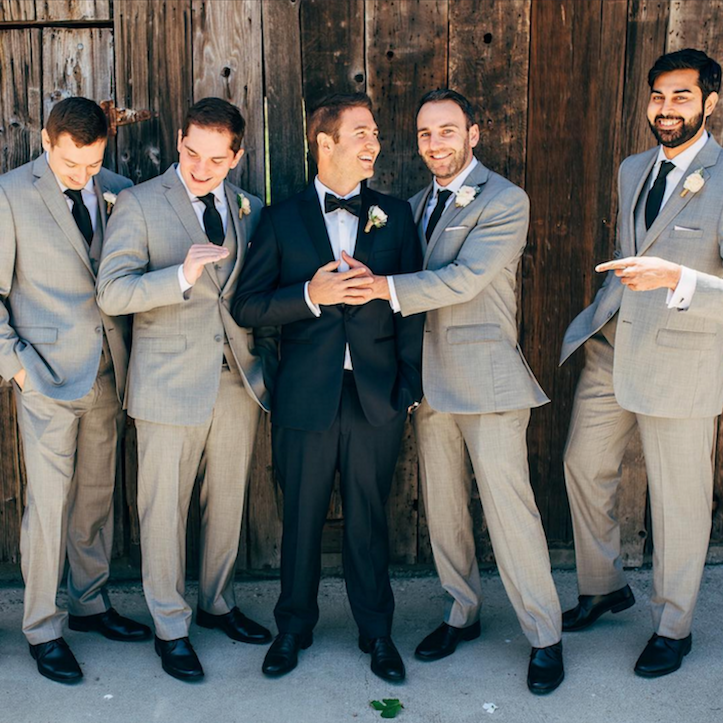 Groom and groomsmen in front of a wooden backdroom.