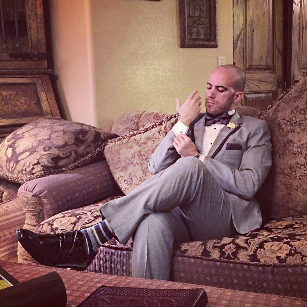 Groom sitting on a couch in a vintage looking photo.