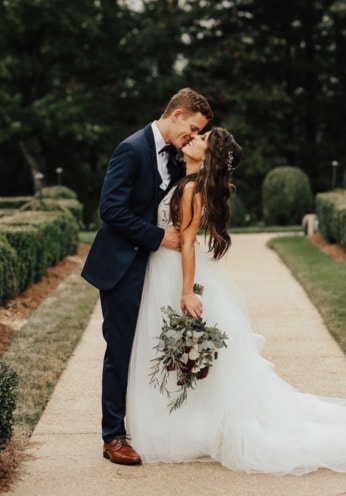 Recently married couple outside kissing on a sunny day.